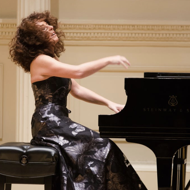 a woman wearing a blac k dress playing the piano